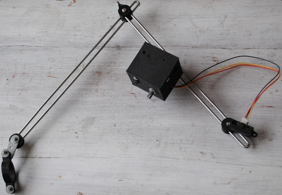 Articulated arm made of double metal rods. On one end, a collar fixes the apparatus on the tripod. Between the two segments, a knee-like joint. On the second segment, the case containing the Arduino, the LED, the switch and the potentiometer. On the last end, the infrared sensor, connected to the case by three wires.